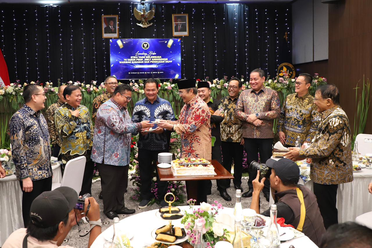 Ketua Bawaslu Rahmat Bagja menerima potongan kue dari Ketua DKPP periode 2012-2017 Jimly Asshiddiqie dalam peluncuran buku Etika yang Melembaga: 70 Tahun Prof. Jimly Asshiddiqie Warisan Gagasan dan Penguatan DKPP, di Jakarta, Jumat (17/4/2026).